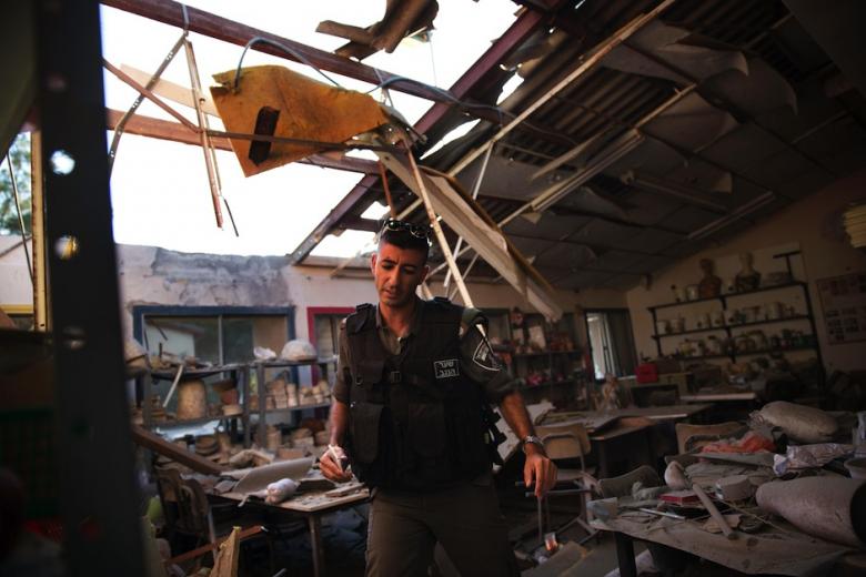 Policial israelense inspeciona edifício em um kibutz perto da fronteira com a Faixa de Gaza em 09 de julho de 2014, depois que foi atingido e danificado por um foguete disparado a partir de Gaza. (Foto: AFP-Menahem Kahana)