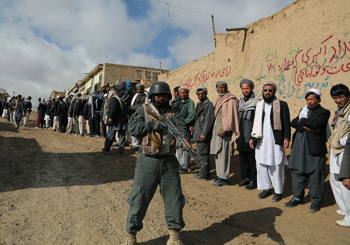 Um policial afegão vigia eleitores afegãos fazendo fila para votar em um posto de votação local em Ghazni em 5 de abril de 2014. (AFP / Rahmatullah Alizadah)